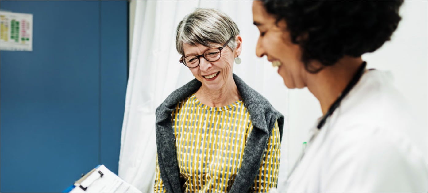 Patient and doctor smiling, doctor is holding clipboard.